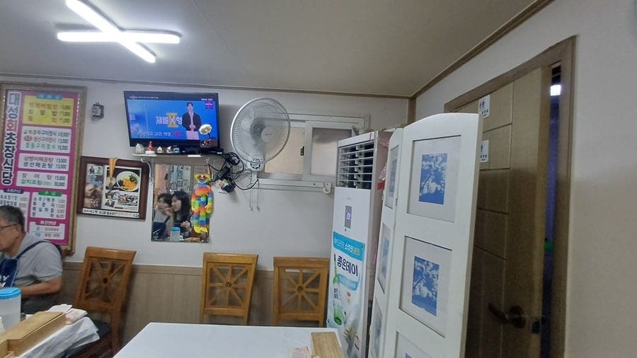 wlsekffo4452이 남긴 실내 사진입니다. 계단 옆 낡은 테이블과 벽에 걸린 방송 출연 사진,