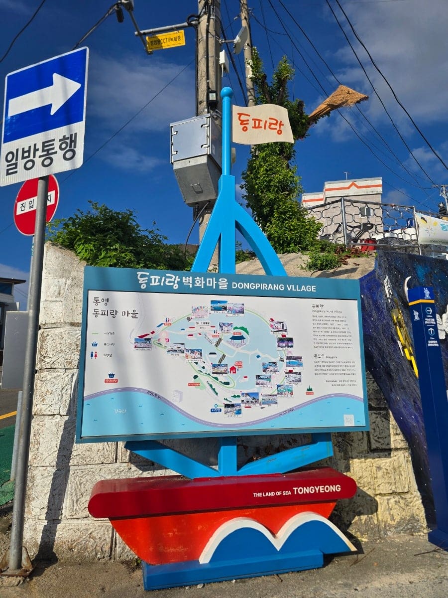 동피랑벽화마을 공식 안내판과 지도, 그리고 '안녕, 동피랑' 인사말이 적힌 초입 벽화입니다. 벽화 축제 현수막도 함께 걸려 있어,