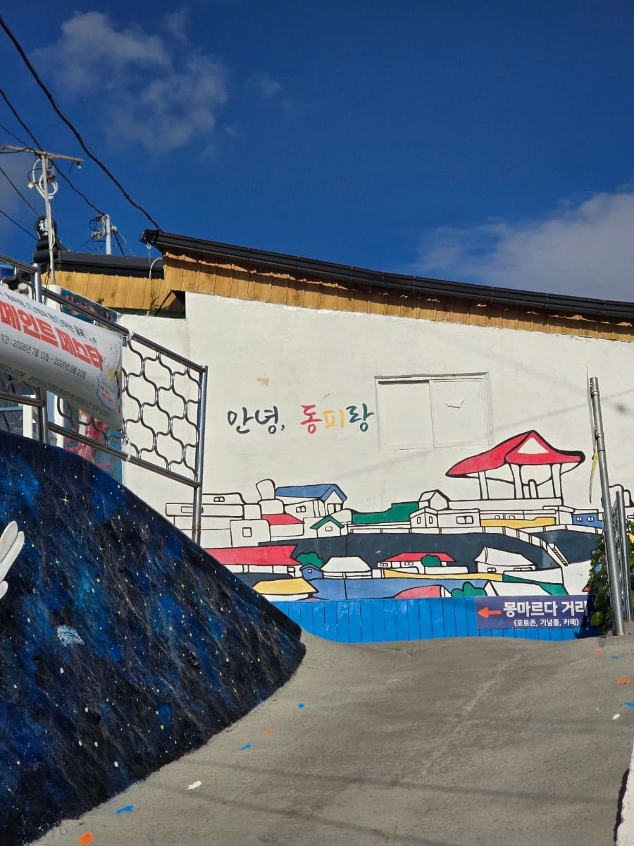 동피랑벽화마을 공식 안내판과 지도, 그리고 '안녕, 동피랑' 인사말이 적힌 초입 벽화입니다. 벽화 축제 현수막도 함께 걸려 있어,