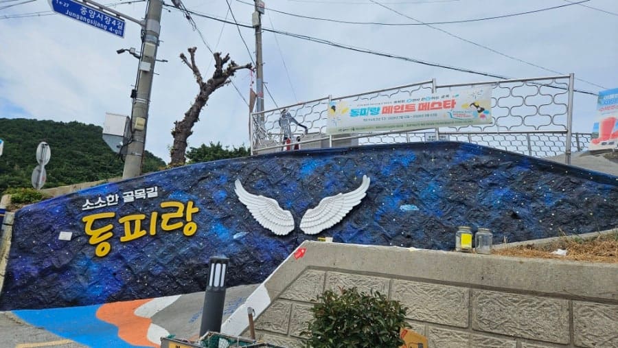 '소소한 골목길 동피랑' 벽화와 벽화 축제 현수막, 그리고 언덕 위에서 내려다본 통영항과 바다입니다. 골목을 다 오른 사람만 만나는 풍경입니다.