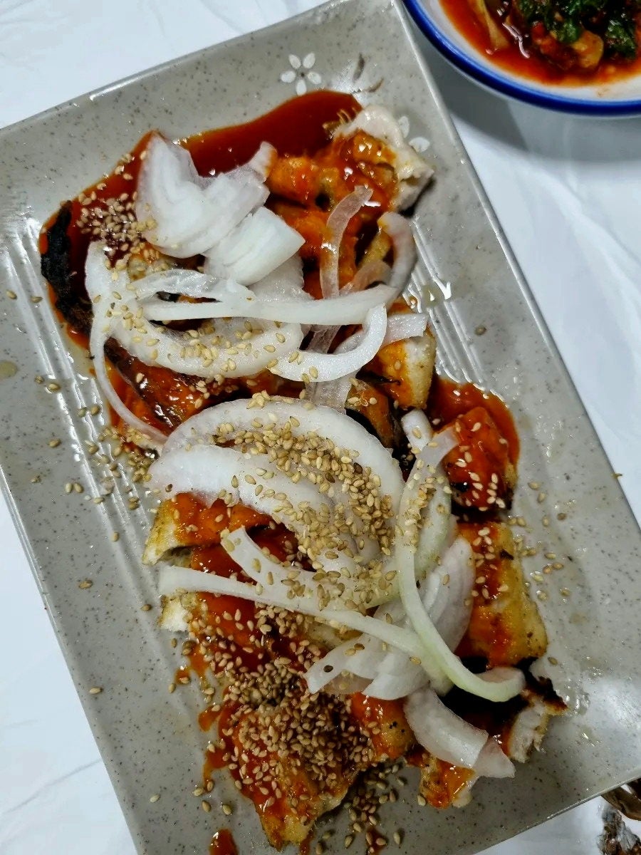 같은 사람이 찍은 생선구이 접시입니다. 양파와 깨를 올려 구운 생선 여러 토막을 가까이서 담았습니다.