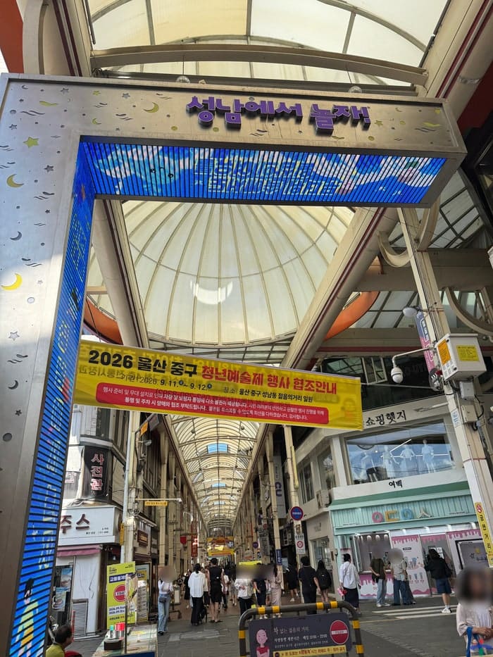 usjunggu가 찍은 청년예술제 현수막과 올리브영 매장 앞 난타 공연입니다. 관에서 마련한 축제 무대가 아케이드와 프랜차이즈 매장을 배경으로 펼쳐지는 모습입니다.