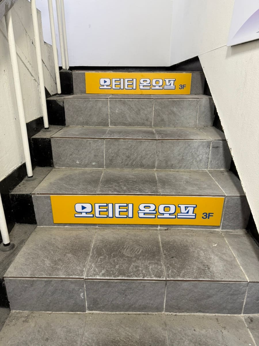 hzlnn_이 남긴 사진입니다. 아케이드 지붕 아래 노란 '오티티온오프' 간판과, 같은 이름이 붙은 계단참 스티커를 함께 찍었습니다.