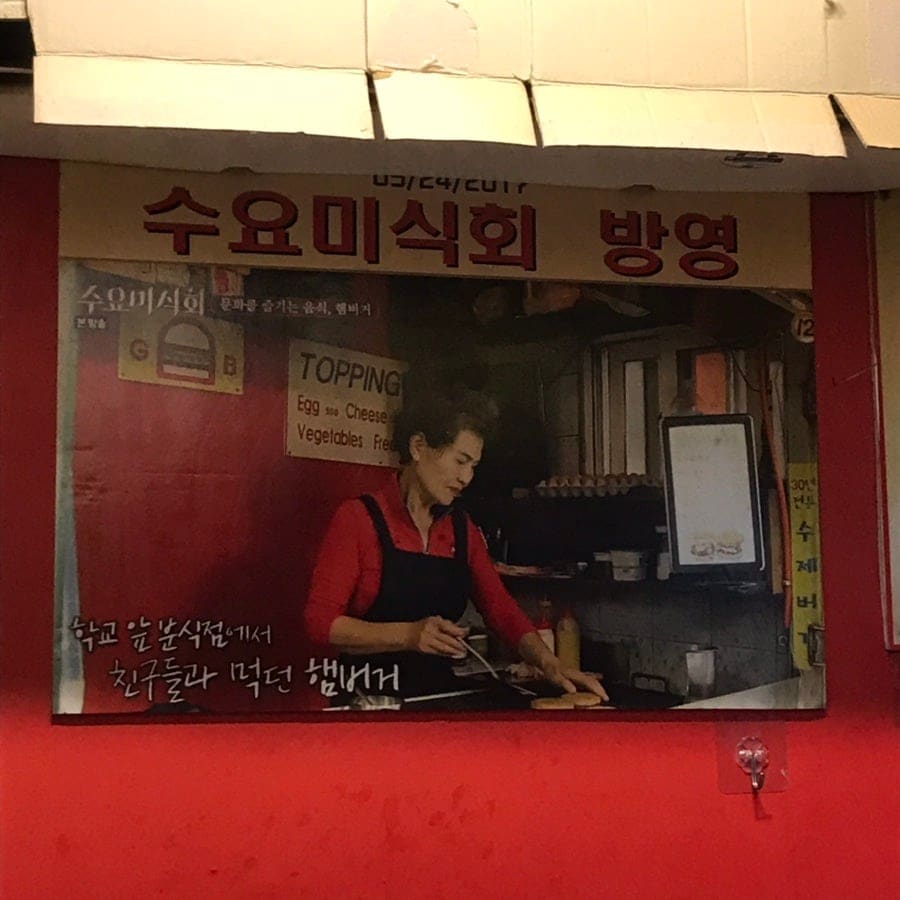 가게 벽에 붙은 오래된 방송 출연 사진과, 지금 그릴 위에서 구워지는 패티와 계란입니다. 지금보다 젊었을 적 요리사의 모습이 담긴 사진 앞에서,