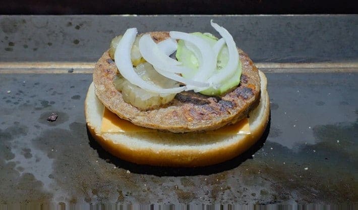 홈스피탈 가이드가 근처 맛집을 소개하며 함께 남긴 사진입니다. 계란과 양파, 피클이 패티 위에 얹힌 모습을 두고,