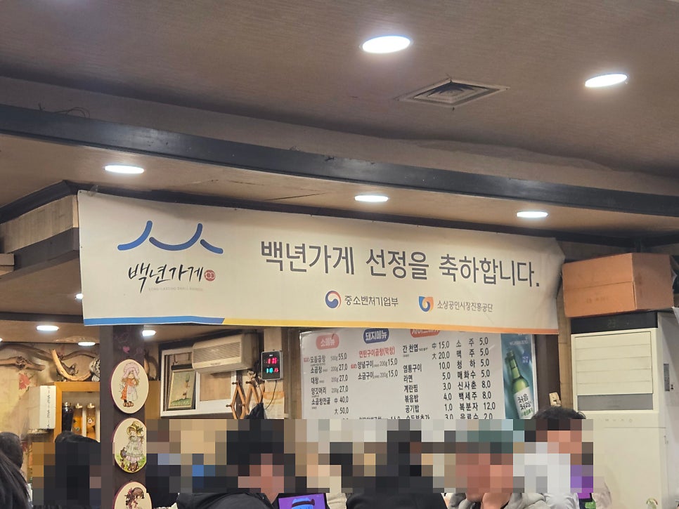 younging_320은 정부네 곱창 내부의 백년가게 선정 현수막과 소·돼지 메뉴판을 담았다. 오래 버틴 가게일수록 벽에 걸어 둘 인증이 늘어난다.
