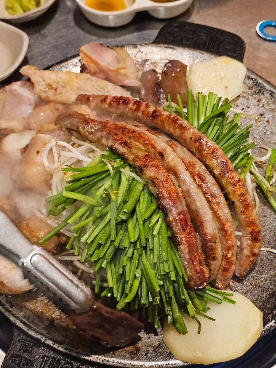 goldtop3321이 화덕에서 초벌로 구워져 나온 곱창과 대창을 가까이서 찍었다. 부추와 콩나물 사이로 기름이 아직 지글거린다.
