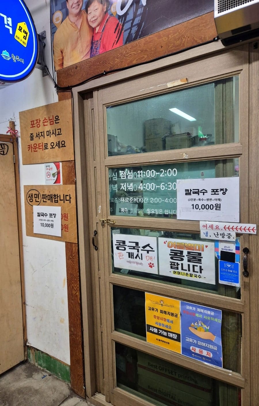 a870226이 찍은 가게 입구입니다. 녹색 간판 아래 '콩국수 판개시', '여름별미 콩물 팝니다' 같은 안내지가 겹겹이 붙어 있고,