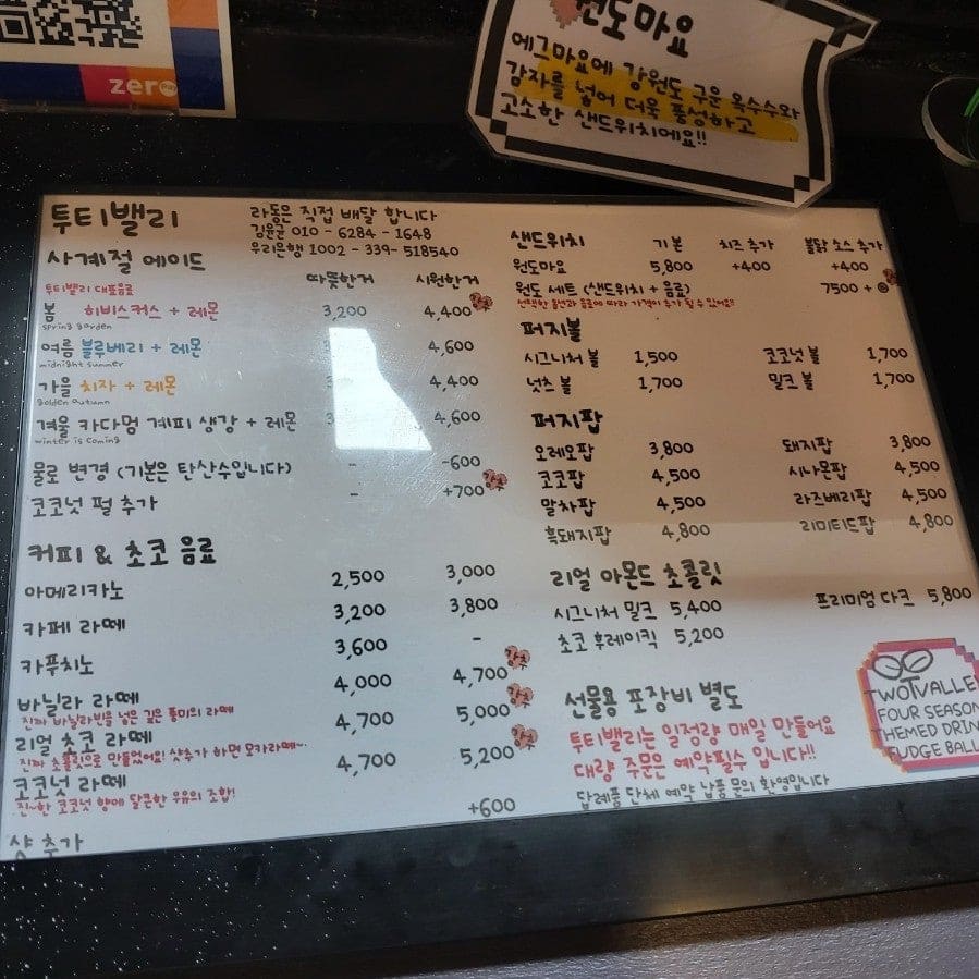 b1nb1n_이 진열장을 가까이서 찍었습니다. 꼬치에 꽂힌 퍼지팝이 종류별로 줄지어 있고, '파지팝 골드', '코코팜·시나몬·말차' 같은 손글씨 가격표가 그 아래 붙어 있습니다.