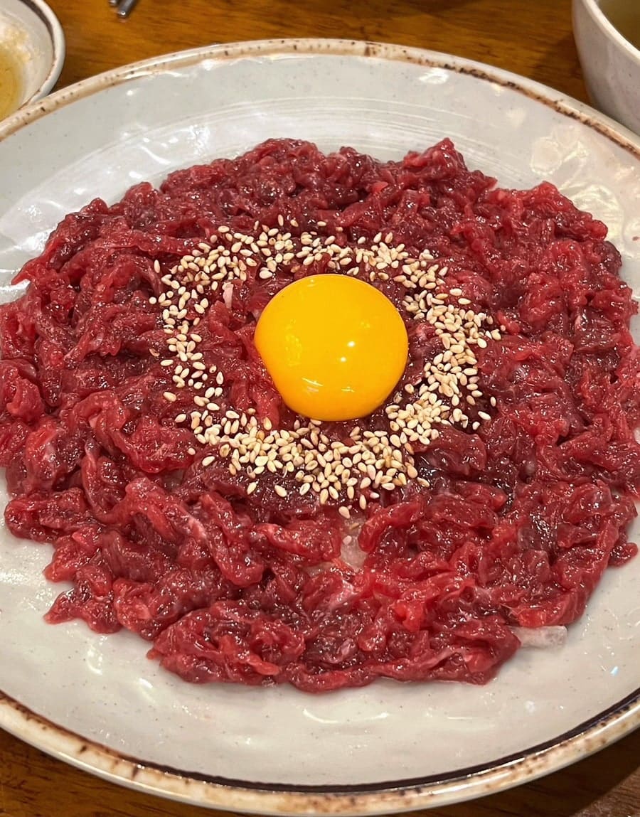 aayonii가 처음 방문했을 때 찍은 육회 상차림입니다. 나무 식탁 위에 육회 한 접시와 소고기무국, 양념장 종지들이 함께 놓였고,
