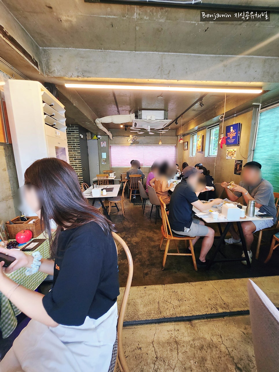 benja7391은 내부가 우드톤 가구와 노출 콘크리트 인테리어가 어우러져 편안한 분위기였다고 적었습니다. 테이블에 앉은 손님들과, 고양이 소품이 놓인 구석 자리가 담겼습니다.