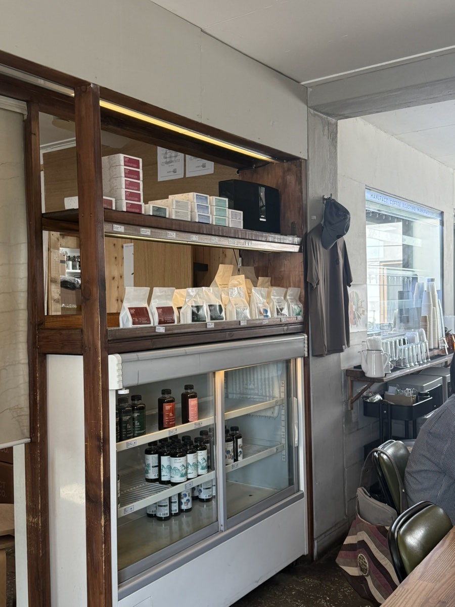 sungji0529는 우유가 커피 맛을 덮지 않고 그대로 살려주는 느낌이었다고 적었습니다. 'MANUFACT COFFEE CO.' 컵이 창틀에 놓여 있고,