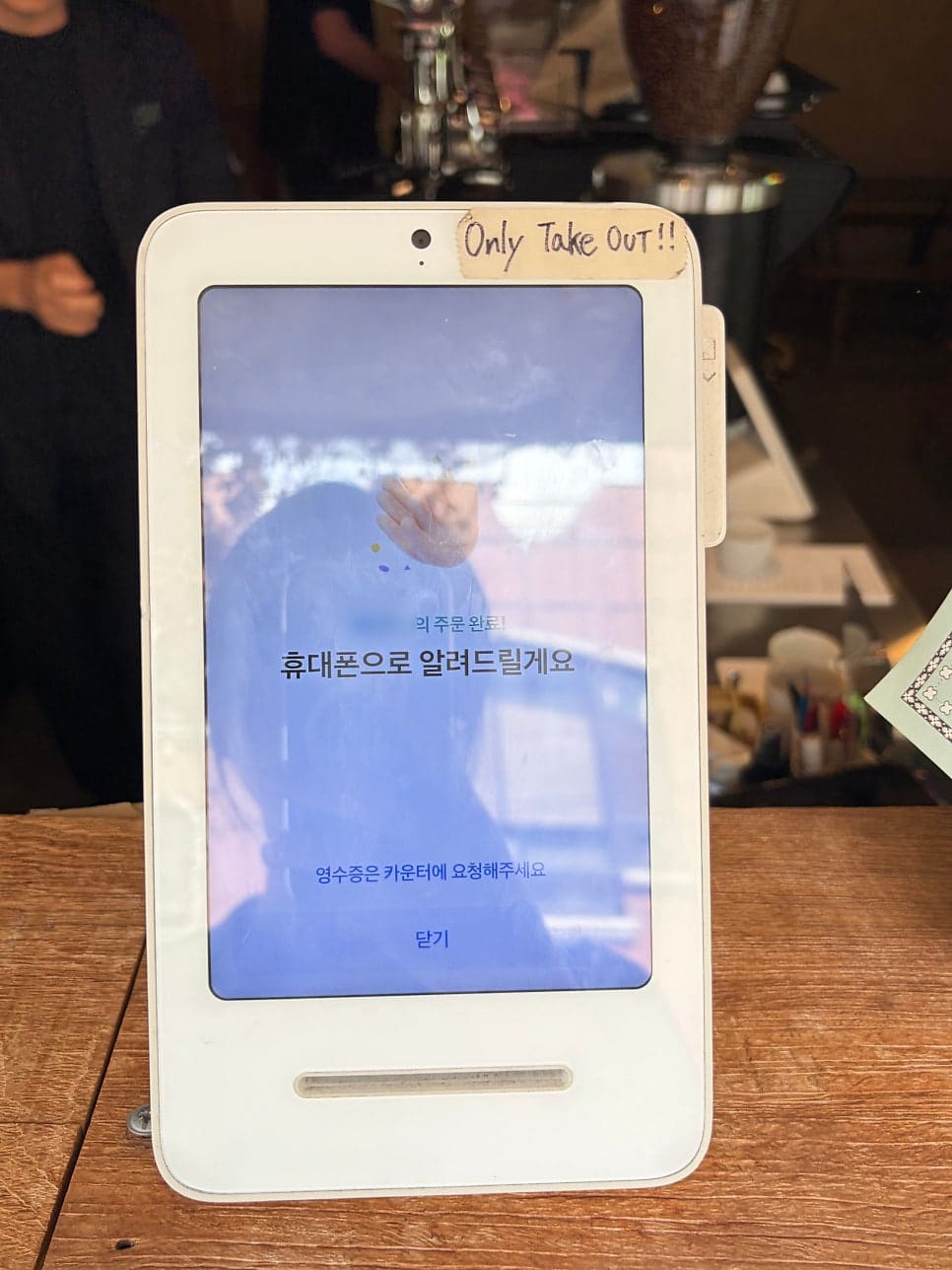 'Only Take Out!!'이라 손글씨로 적어둔 주문 키오스크와, 입구 앞에서 얌전히 기다리는 손님의 반려견입니다.