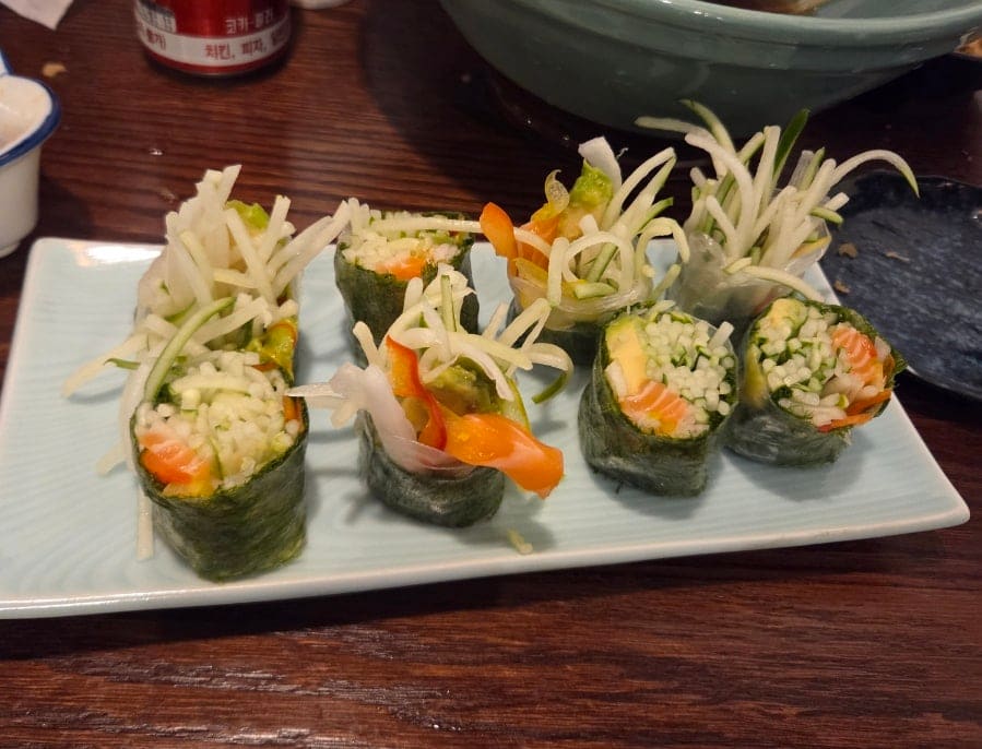 무와 오이를 얇게 채썰어 두른 롤 요리와, 여러 재료를 채운 두툼한 김밥 한 조각입니다. 우동집이지만 곁들임 메뉴에도 정성이 담겨 있다고 블로거는 적었습니다.