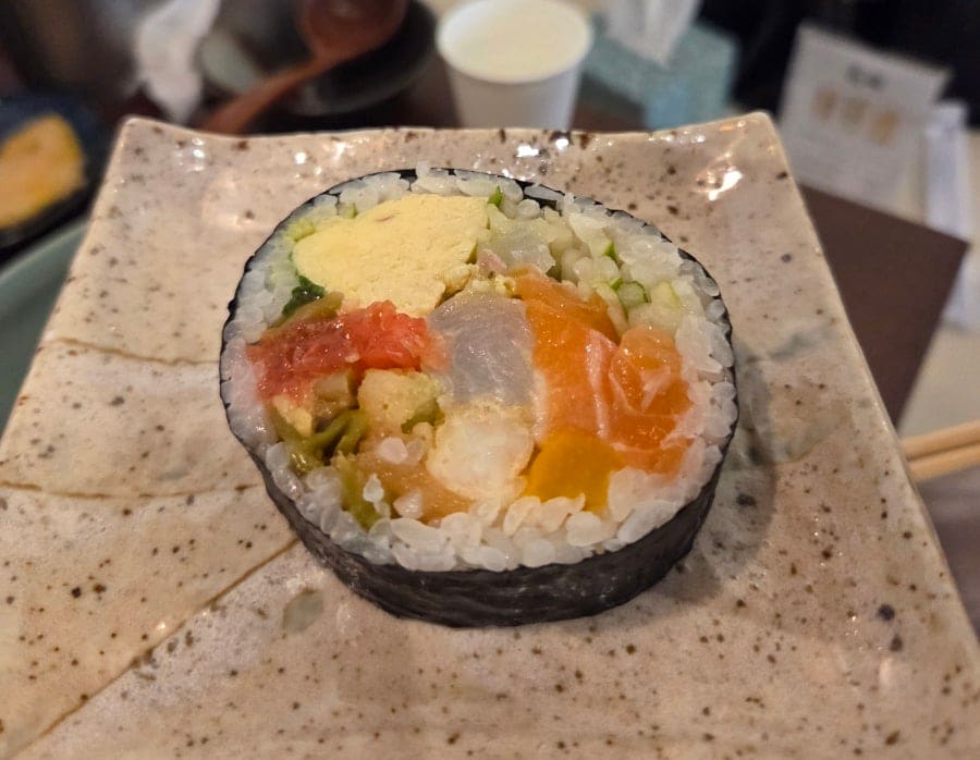 무와 오이를 얇게 채썰어 두른 롤 요리와, 여러 재료를 채운 두툼한 김밥 한 조각입니다. 우동집이지만 곁들임 메뉴에도 정성이 담겨 있다고 블로거는 적었습니다.