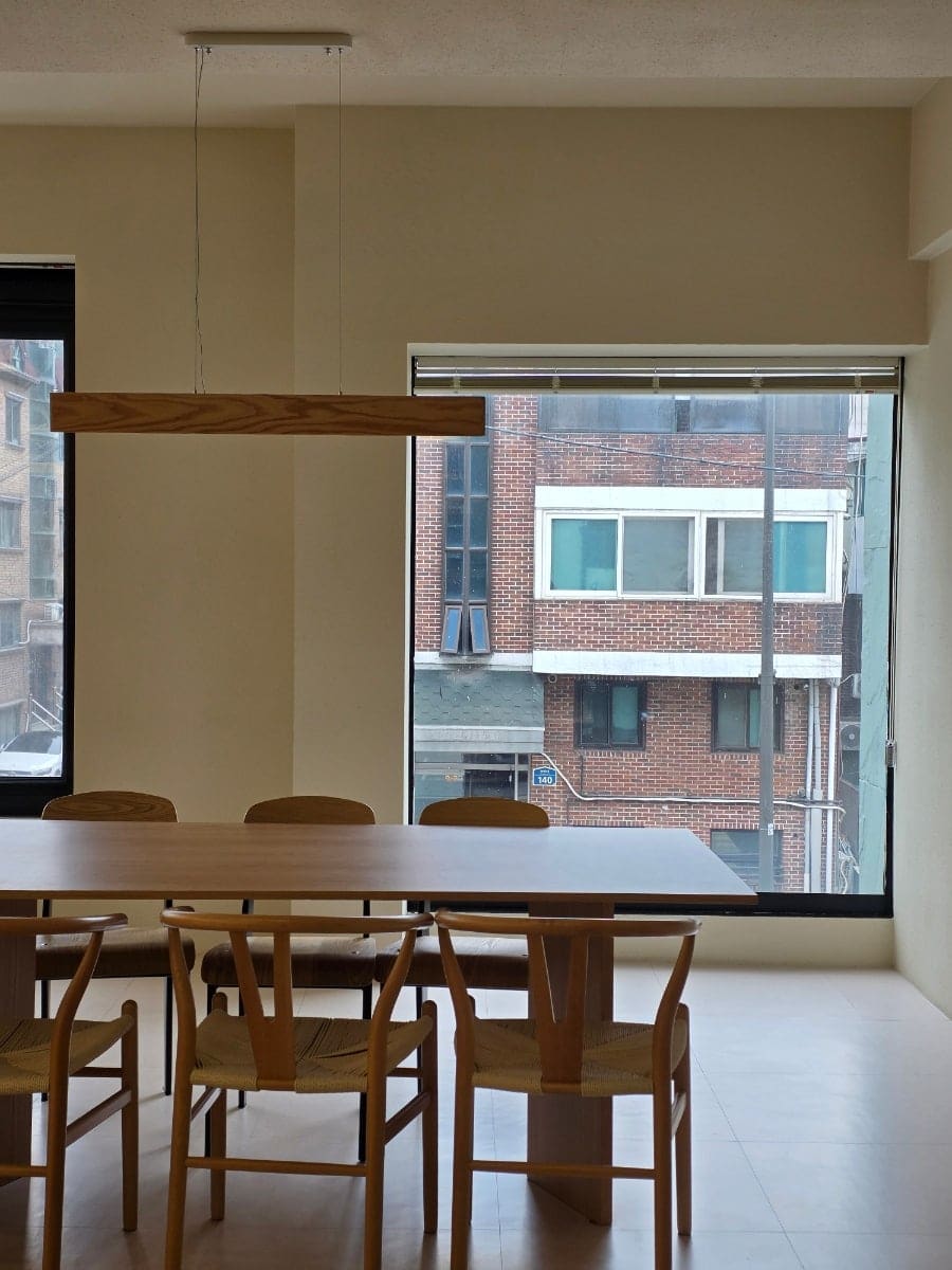미니멀한 원목 식탁과 창밖 붉은 벽돌 건물, 그리고 인도에 세워둔 'CAFE' 입간판입니다. 커피와 티,