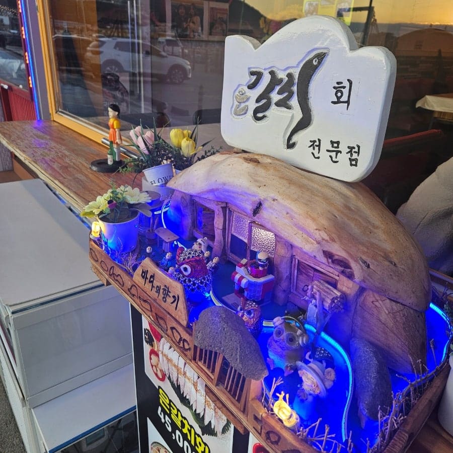 dahye2605가 담은 낮 시간의 실내와 가게 앞 미니어처 장식입니다. 붉은 조명 아래 소파형 좌석이 줄지어 있고,