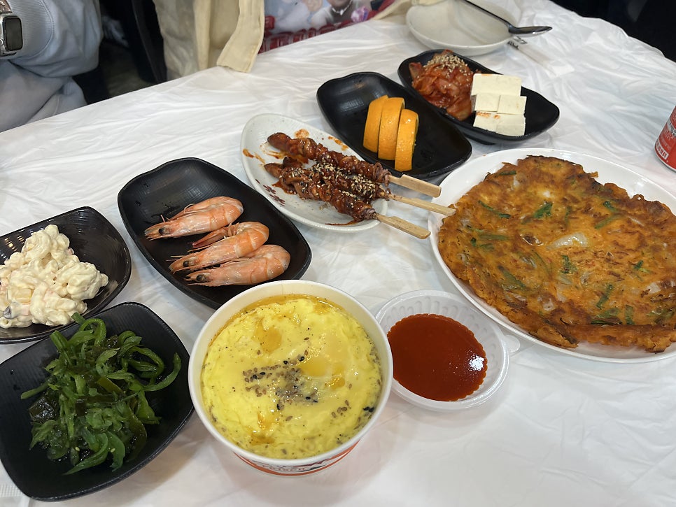 da_eeee가 담은 벽면과 상차림입니다. 선반 아래로 손님들이 남긴 낙서가 벽 전체를 빼곡히 채우고 있고, 새우와 계란찜, 해초, 두부김치,