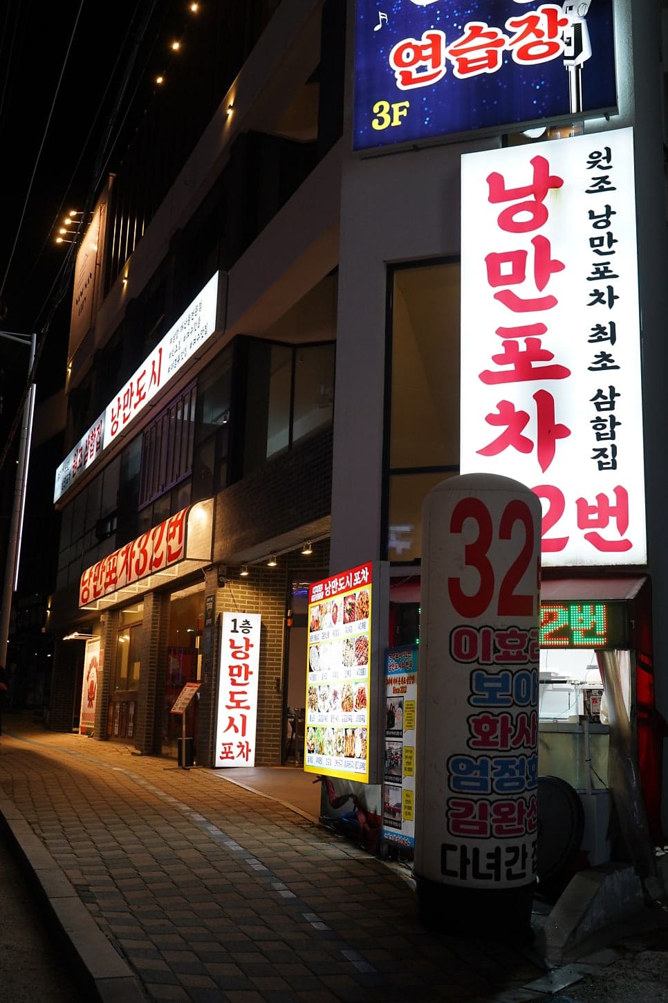 lamanoworks가 담은 밤의 외관과 안내판입니다. '낭만포차32번' 간판이 빨갛게 빛나고,