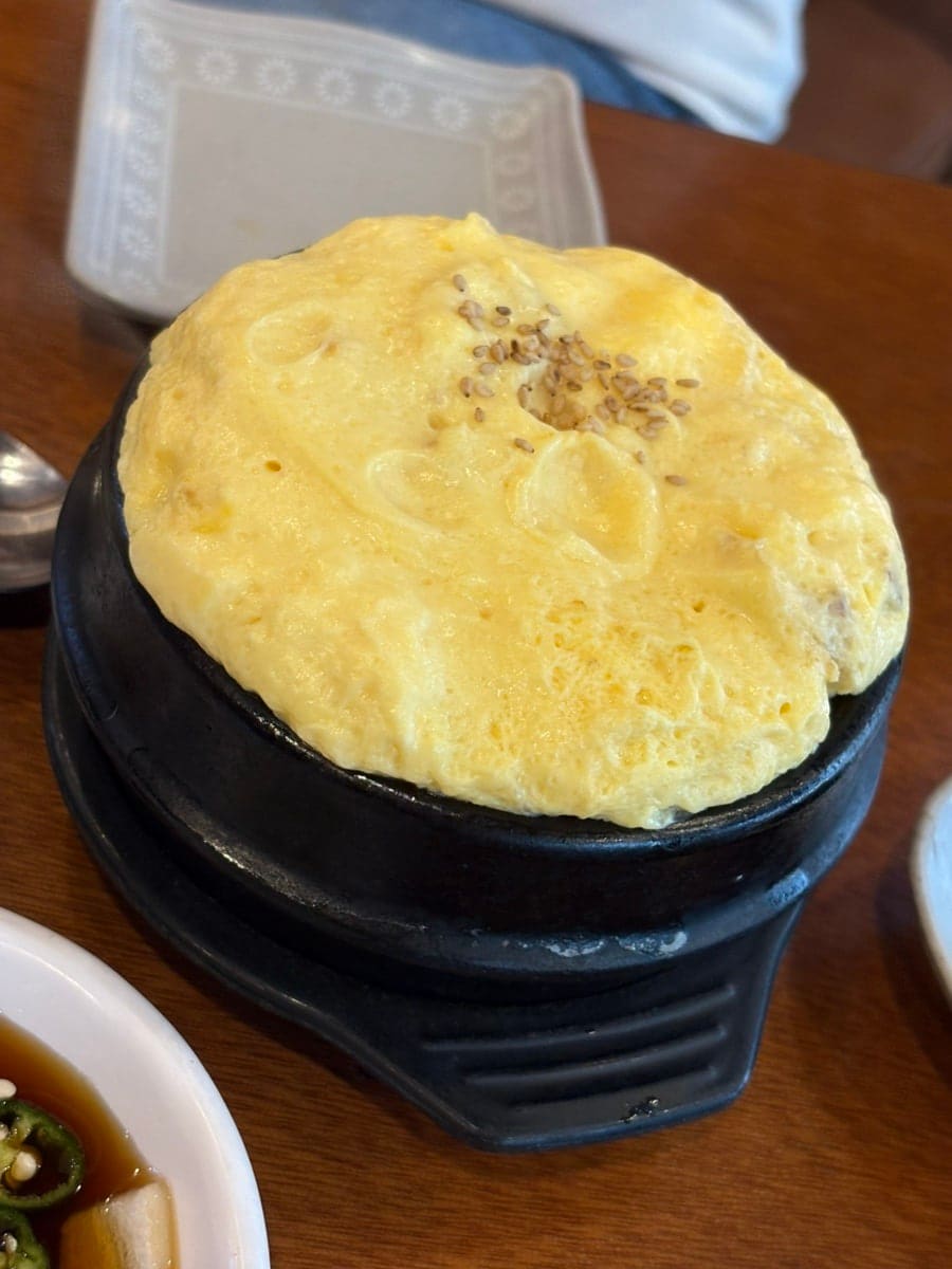 junotes는 고기만 덜렁 나오는 느낌이 아니라 여러 가지 반찬이 함께 차려져 한정식처럼 상이 꽉 찬다고 적었습니다. 나물과 김치 반찬이 접시마다 놓인 테이블과,