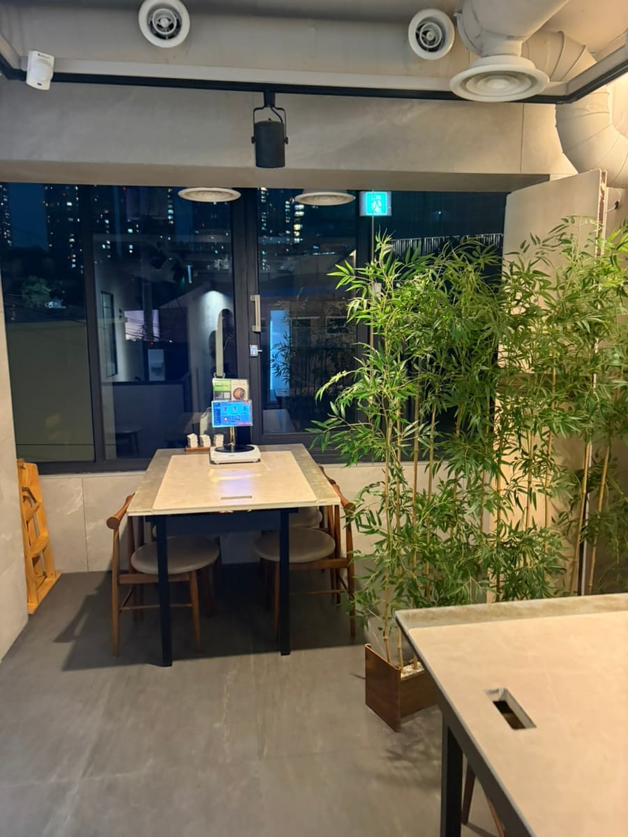 dahoon9296은 나무 창살 가림막으로 나뉜 좌석과, 밤이 내려앉은 통창 너머 대나무 화분을 함께 남겼습니다. 낮게 드리운 조명 아래 마주 앉은 손님들의 모습과,