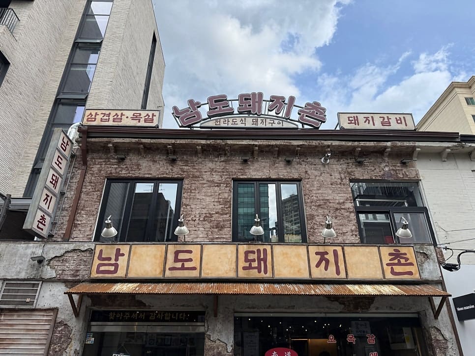 dustella는 물이 보리차로 나오는 순간부터 첫인상이 합격이었다고 적었습니다. 하늘이 걸린 간판 아래 벽돌 건물의 외관과,